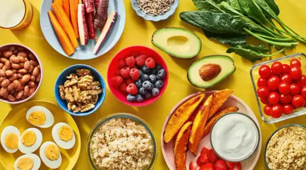 En färgsprakande dukning med proteinrik vegetarisk mat: bönor, ägg, nötter, bär, grönsaker och quinoa.