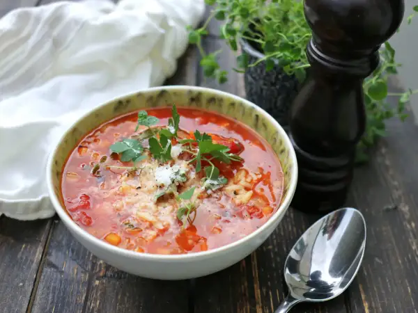 En mustig tomatsoppa med ris och örter, en perfekt källa till vegetariskt protein. Serveras med en sked och pepparkvarn.